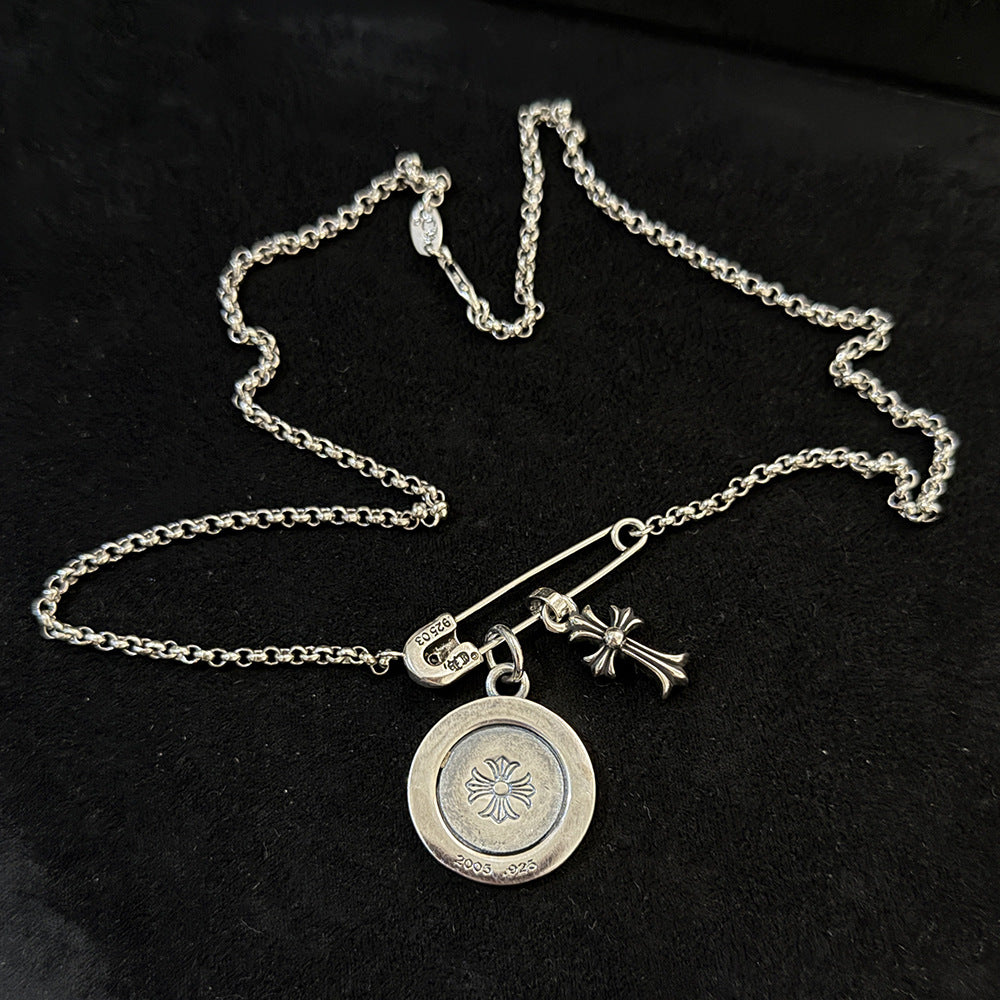 Chrome Hearts brooch with cross and diamond-encrusted round pendant.