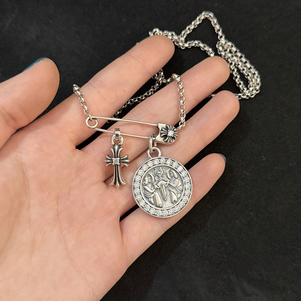 Chrome Hearts brooch with cross and diamond-encrusted round pendant.