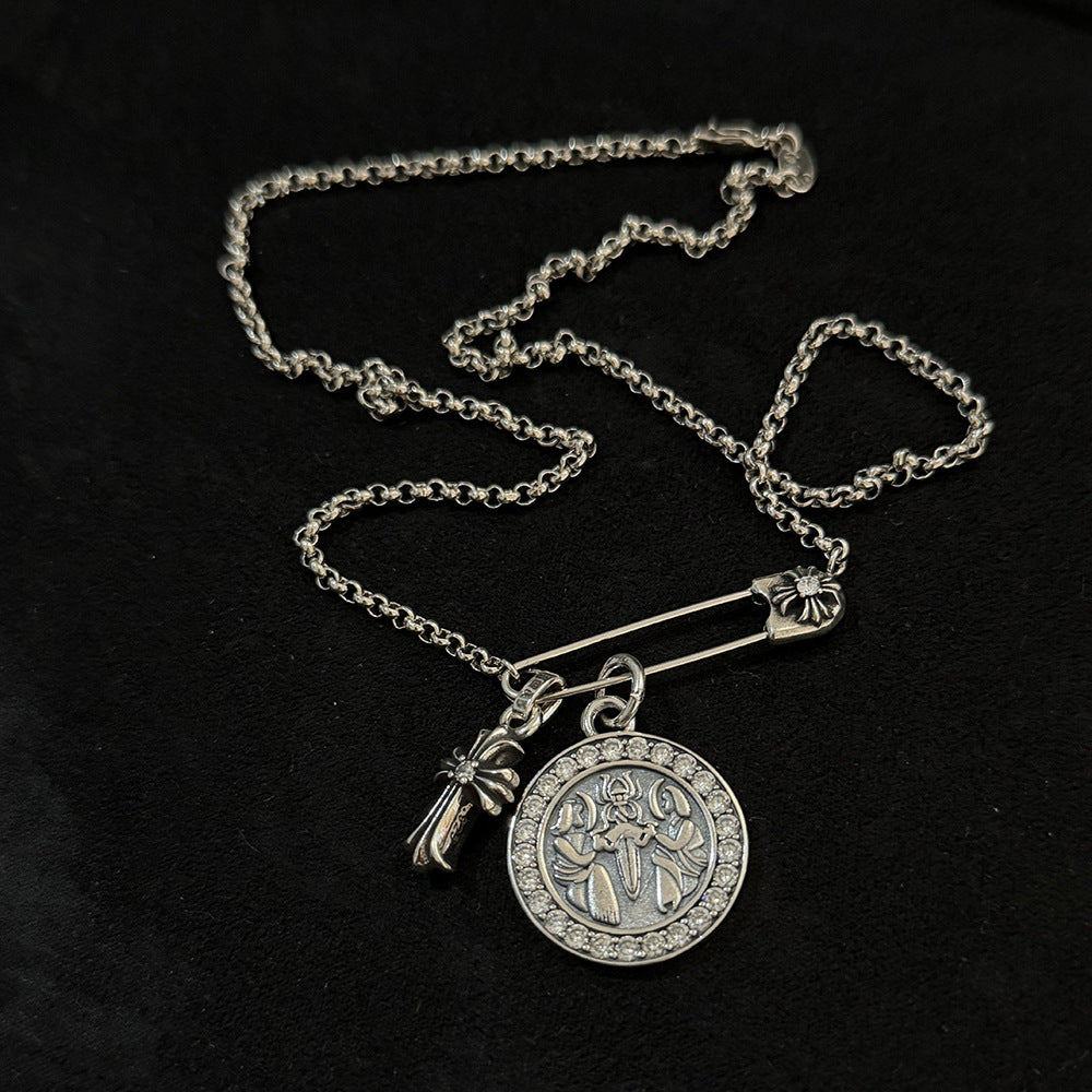 Chrome Hearts brooch with cross and diamond-encrusted round pendant.
